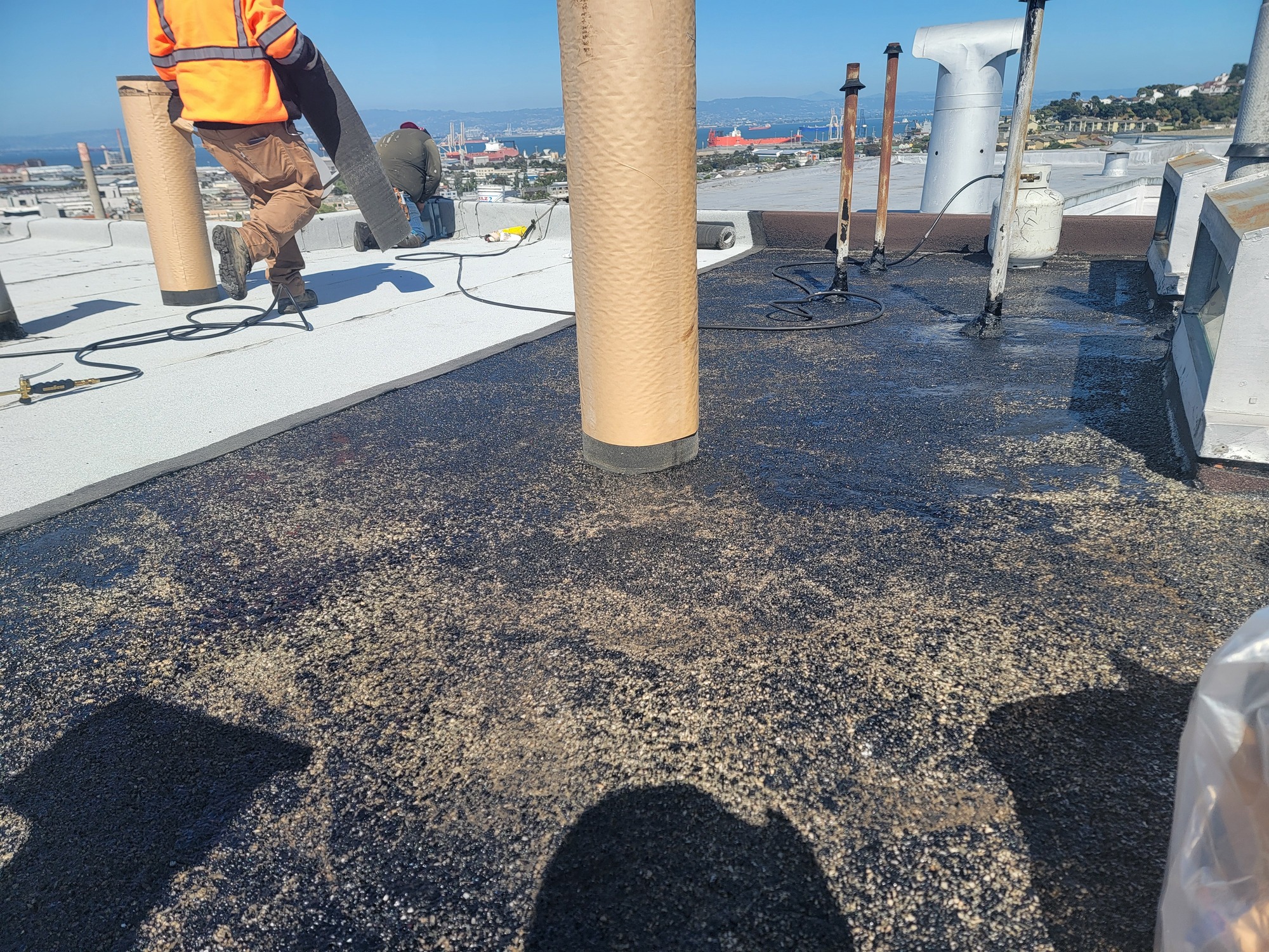 Crew torching down new flat roof membrane on a San Francisco building overlooking the Bay