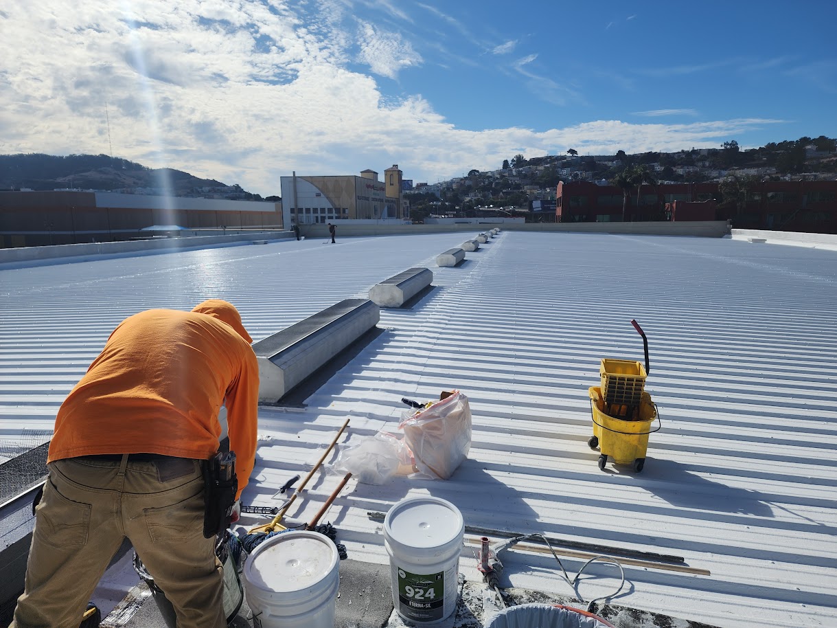 Ace Roofing crew applying reflective white coating to a large SF metal roof