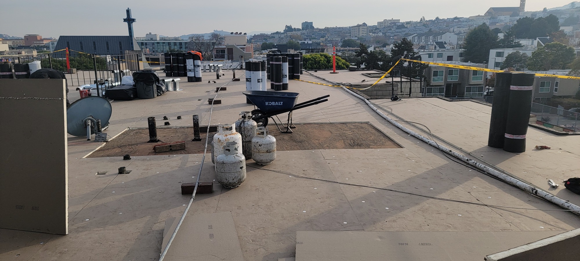 Flat roof prepped for torch-down installation with new base sheet and propane tanks staged