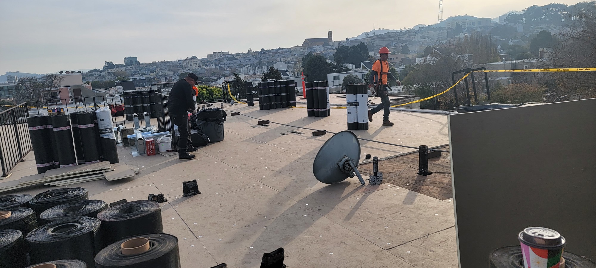 Stacked rolls of torch-down modified bitumen ready for installation on an SF rooftop