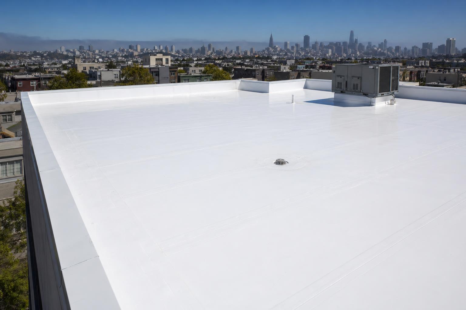 Newly installed white TPO single-ply membrane flat roof on a San Francisco commercial building with skyline view